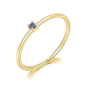 Close-up of minimalist gold ring featuring a four-prong set round blue gemstone
