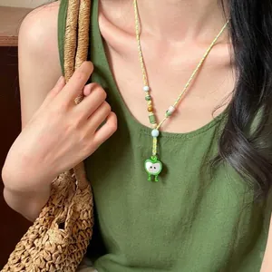 Detailed shot of green apple pendant necklace with colorful beads on woven cord