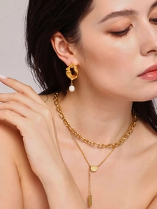 Gros plan détaillé des boucles d'oreilles dorées à texture lave et perles en gouttes