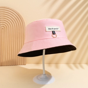 Dettaglio cappello alla pescatora rosa con patch How do you do? e nastro MU su anello