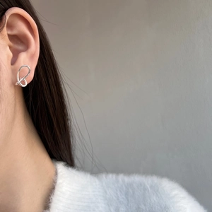 Detailed view of silver butterfly wing earrings with minimalist hollow lines on model ear