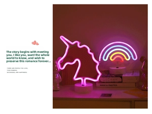 Detail of neon LED unicorn and rainbow decorative lamps on round white stands