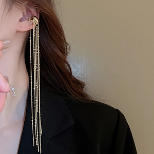 Close-up of gold chain tassel ear cuff with irregular texture on elegant model