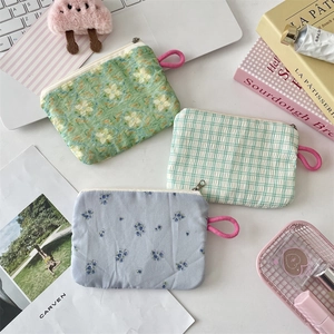 Three assorted floral fabric pouches with zippers set on a desk with a laptop and books