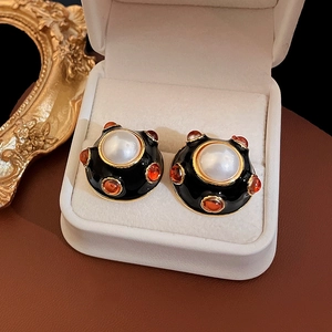 Vue macro des boucles d'oreilles vintage avec émail noir, perle et perles oranges