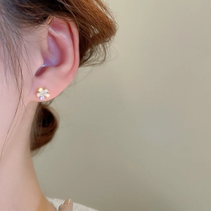 Gros plan sur un élégant clou d'oreille fleur en or avec zircon sur l'oreille du mannequin