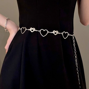 Detailed view of silver heart-shaped cutout waist chain on a black dress background