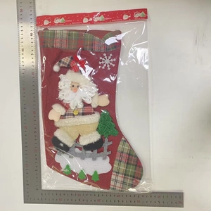 Detailed view of large Christmas stocking with Santa doll and green tree decorations