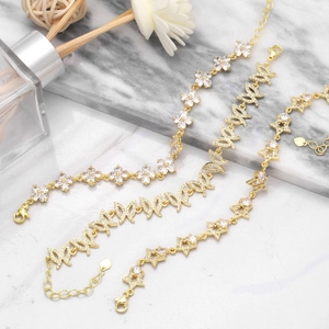 Detailed view of three gold bracelets featuring floral, leaf, and star zircon charms