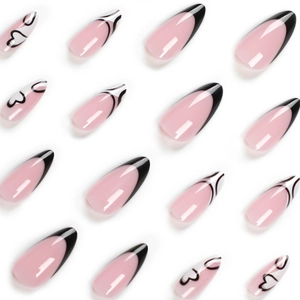 Pink almond press-on nails with black French tips and heart patterns on white background
