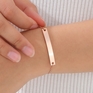 Close-up of minimalist rose gold bar bracelet worn by a model on a white knit background