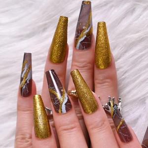 Long coffin fake nails with brown marble texture and gold glitter on white plush background