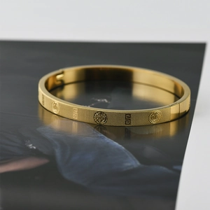 Close-up of gold titanium steel bangle with grid texture and religious medal engravings