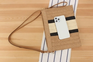Straw envelope bag size comparison with smartphone on light wood background