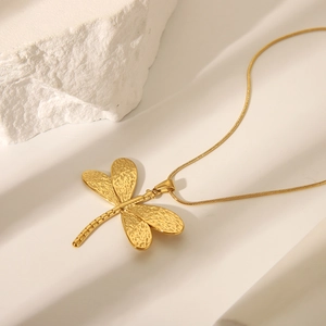 Detail of golden dragonfly pendant with textured wings on a sleek snake chain necklace