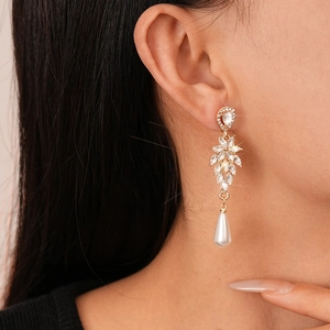 Detail of elegant gold drop earrings with sparkling marquise crystals and white faux pearl