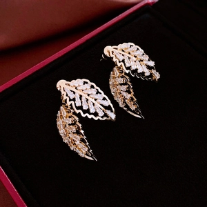 Détail macro de boucles d'oreilles feuilles avec zircons brillants sur velours noir