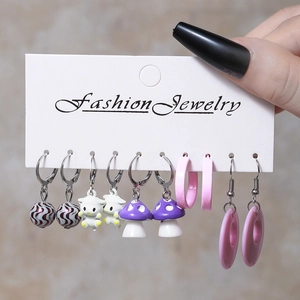 Close-up of creative resin earring set featuring mushroom and ball charms held in hand