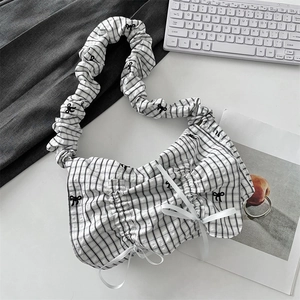 Close-up of pleated shoulder bag with black bow patterns and white ribbon details