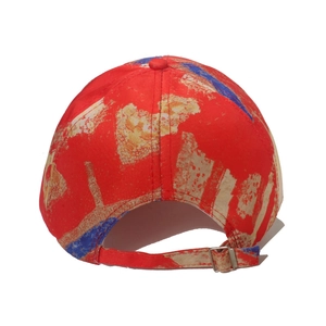Detail view of red baseball cap back with colorful paint splatters and adjustable metal buckle