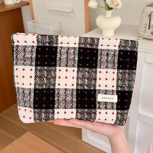 Close-up of hand holding a black and white checkered plaid makeup bag with red dots