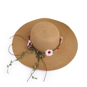 Detailed close-up of woven straw texture and decorative pink flowers on sun hat