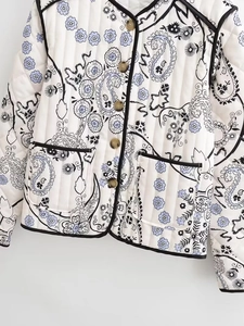 Detail of quilted women jacket with paisley floral print and contrast black piping trim