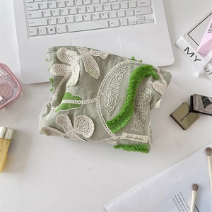 Detailed embroidery of 3D flowers on a green cosmetic bag with stylish tassel trim