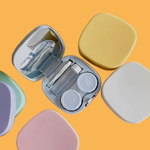 Detail of macaron color contact lens cases with mirror, tweezers, and suction tool