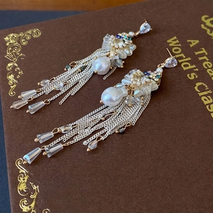 Baroque pearl bow tassel earrings with zircon stones on a vintage book surface