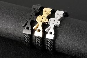 Detailed view of skull and pistol charms on braided leather bracelets for men