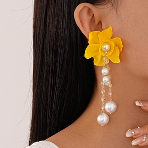 Macro detail of oversized yellow lace flower earring with dangling pearls and crystal beads