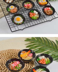 Macro detail of miniature Japanese ramen bowl keychains with realistic shrimp and egg topping