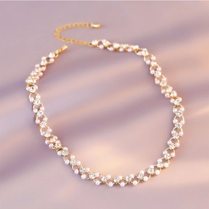 Elegant gold pearl choker necklace with sparkling crystals on soft purple fabric