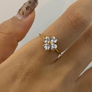 Close-up of a gold clover ring with four heart-shaped zircons on a woman's finger