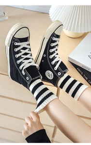 Close-up of black high-top sneakers with striped crew socks in a cozy home setting