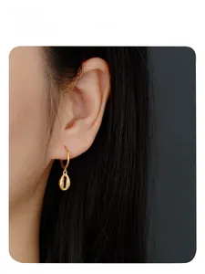 Detail of s925 silver gold seashell drop earrings worn by a model in a close-up shot