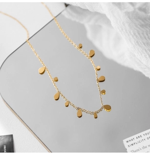 Detailed macro shot of golden teardrop charms on a fine stainless steel chain