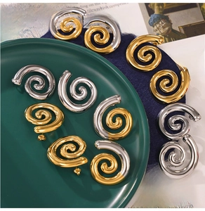 Vue détaillée des boucles d'oreilles spirales géométriques dorées et argentées polies