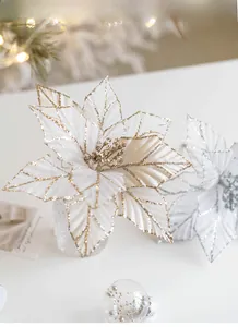 Detail of white velvet Christmas poinsettia flowers with gold glitter edges and festive props