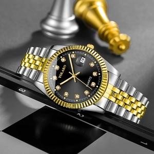 Macro detail of quartz watch dial with gold markers, date window and two-tone steel band