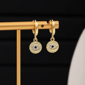 Close-up of gold evil eye drop earrings with blue stone and sparkling zircon pavé