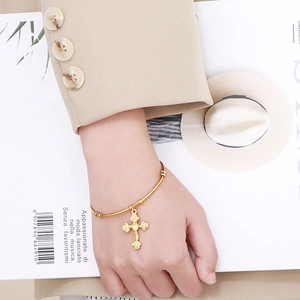 Elegant gold-tone titanium steel cuff bracelet featuring a rose floral cross pendant