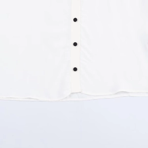 White shirt with black button contrast detail and minimalist tiered layering style