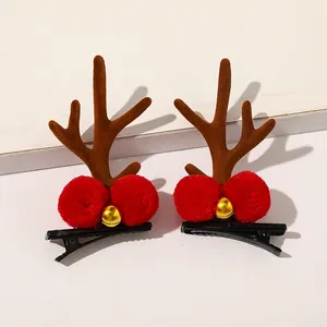 Close-up of Christmas reindeer antler hair clips with red plush balls and golden bells