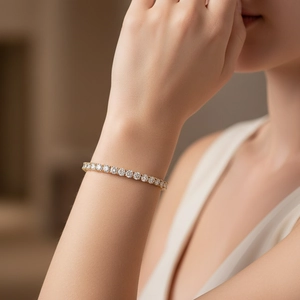 Primo piano di un bracciale tennis dorato con zirconi indossato sul polso di una donna