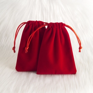 Red velvet drawstring pouch for jewelry storage on a white plush background