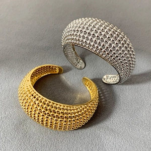 Detail von breiten Metallarmreifen mit Perlenstruktur in Gold- und Silberoptik