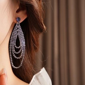 Detail of elegant purple layered rhinestone drop earrings worn by a model in warm light