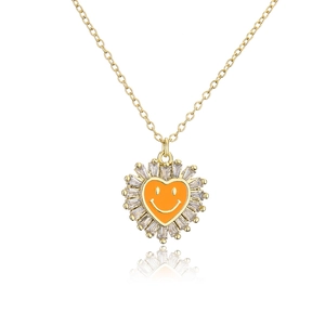 Detail of gold heart pendant with orange smiley face and clear zircon border